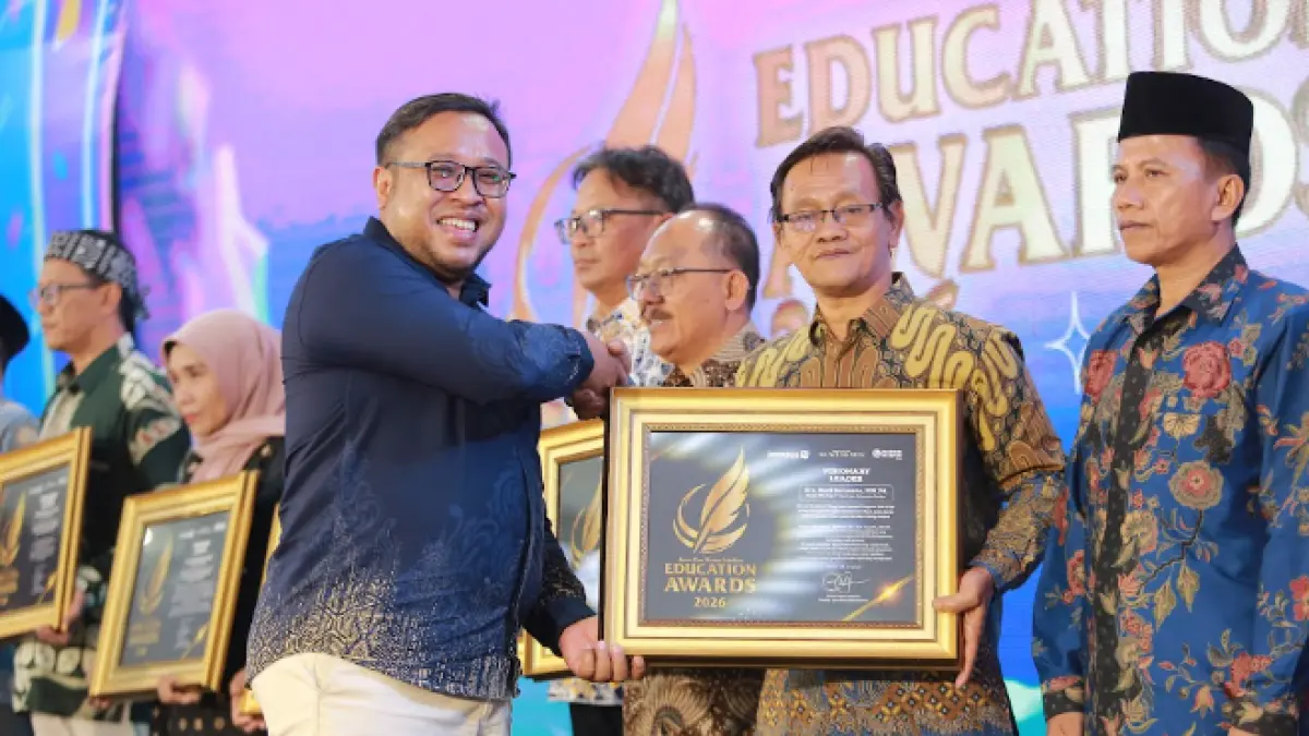 Direktur Jawa Pos Radar Madiun Ockta Prana Lagawira menyerahkan penghargaan Visionary Leader kepada Kepala SMAN 1 Ngadirojo Budi Suryanto dalam ajang Radar Madiun Education Awards 2026, Minggu (28/6). (BAGAS BIMANTARA/RADAR MADIUN)