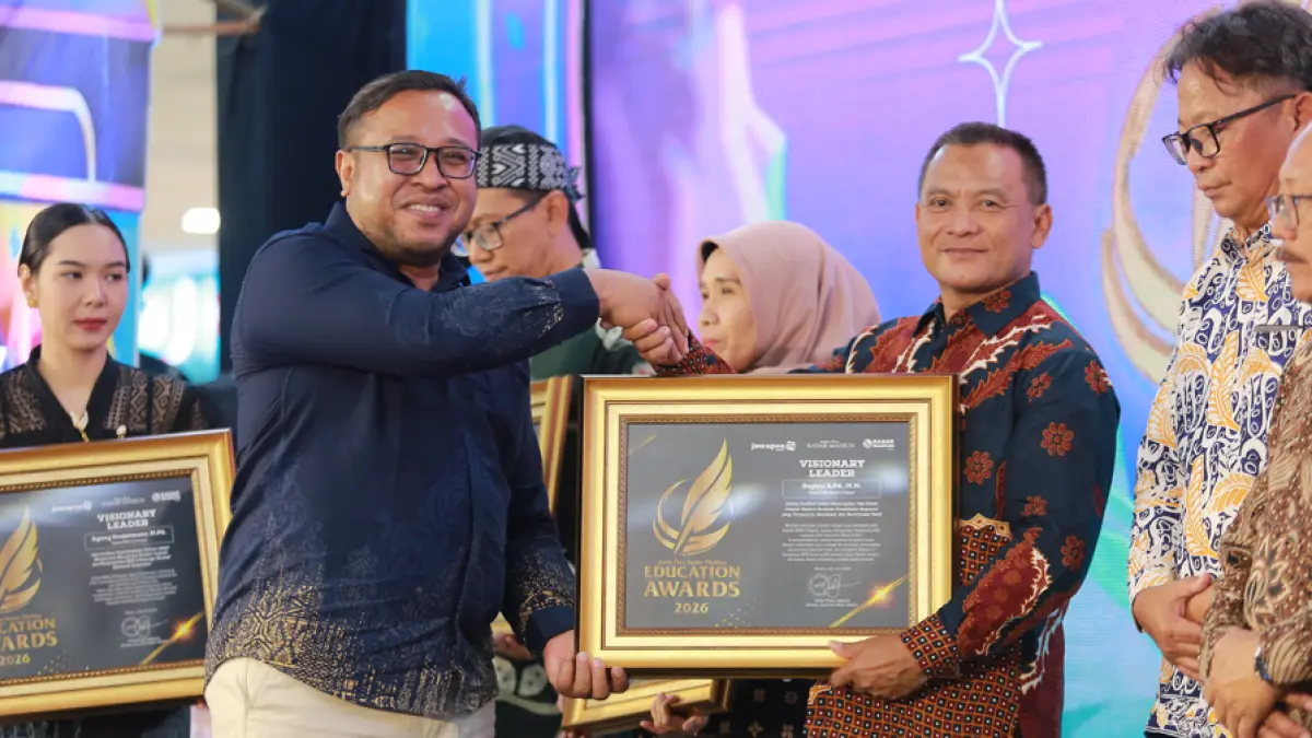 Direktur Jawa Pos Radar Madiun Ockta Prana Lagawira menyerahkan penghargaan Visionary Leader kepada Kepala SMAN 2 Ngawi Sugiyo dalam ajang Radar Madiun Education Awards 2026, Minggu (28/6). (BAGAS BIMANTARA/RADAR MADIUN)