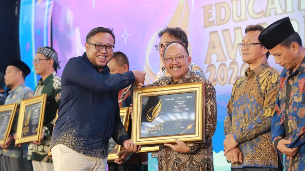 Direktur Jawa Pos Radar Madiun Ockta Prana Lagawira menyerahkan penghargaan Visionary Leader kepada Kepala SMAN 2 Ponorogo Mursid dalam ajang Radar Madiun Education Awards 2026, Minggu (28/6).
