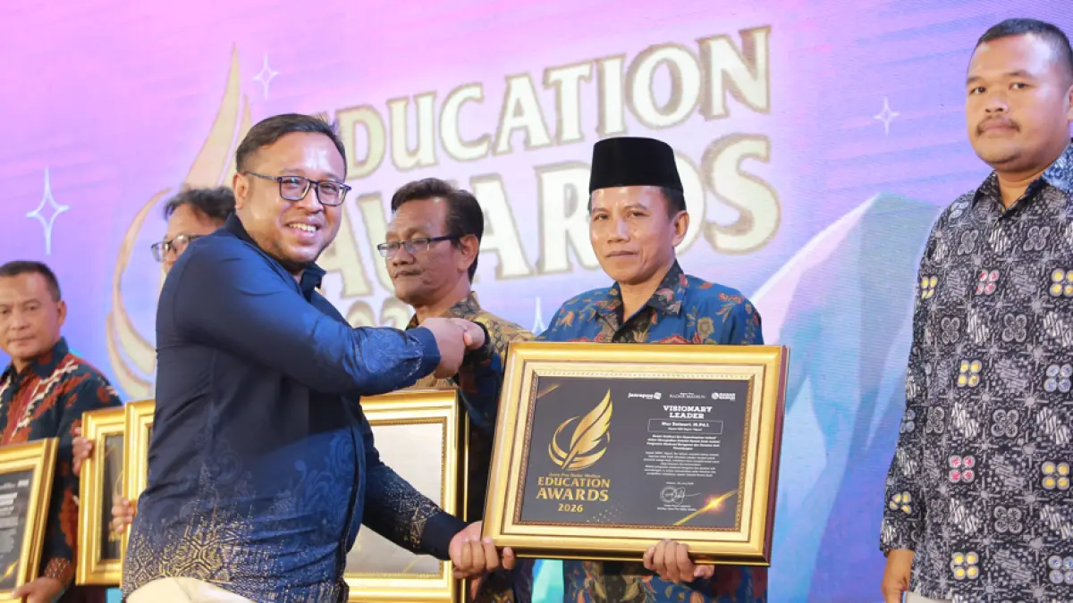 Direktur Jawa Pos Radar Madiun Ockta Prana Lagawira menyerahkan penghargaan Visionary Leader kepada Kepala SMKN 1 Ngawi Nur Zainuri dalam ajang Radar Madiun Education Awards 2026, Minggu (28/6). (BAGAS BIMANTARA/RADAR MADIUN)