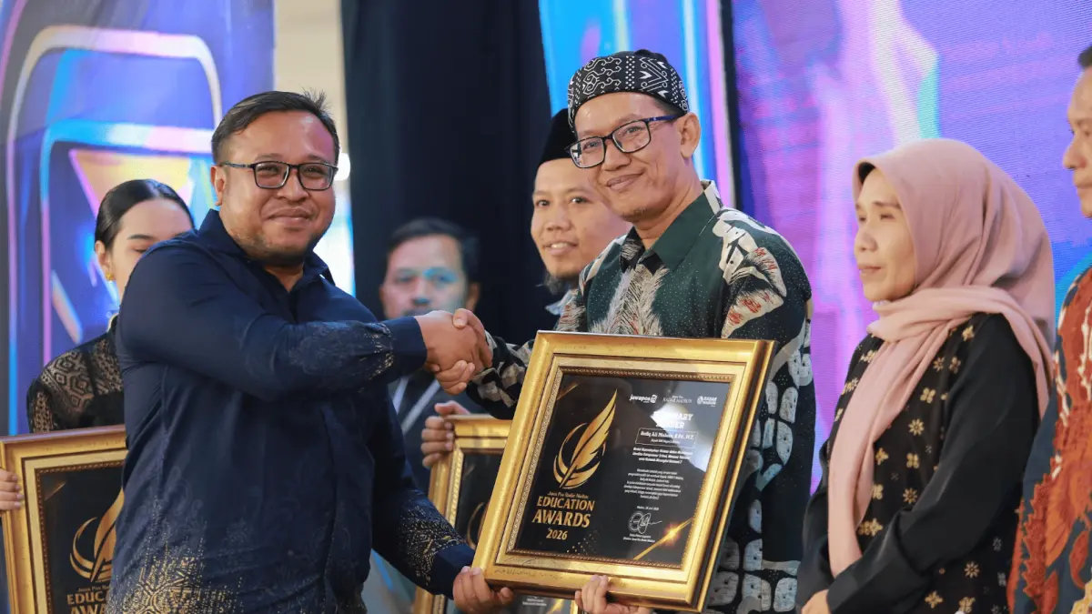 Direktur Jawa Pos Radar Madiun Ockta Prana Lagawira menyerahkan penghargaan Visionary Leader kepada Kepala SMKN 5 Madiun Rofiq Ali Muhsin dalam ajang Radar Madiun Education Awards 2026, Minggu (28/6). (BAGAS BIMANTARA/RADAR MADIUN)