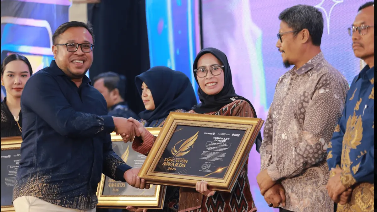 Direktur Jawa Pos Radar Madiun Ockta Prana Lagawira menyerahkan penghargaan Visionary Leader kepada Kepala SMPN 1 Geneng Oviella Yuwono dalam ajang Radar Madiun Education Awards 2026, Minggu (28/6). (BAGAS BIMANTARA/RADAR MADIUN)