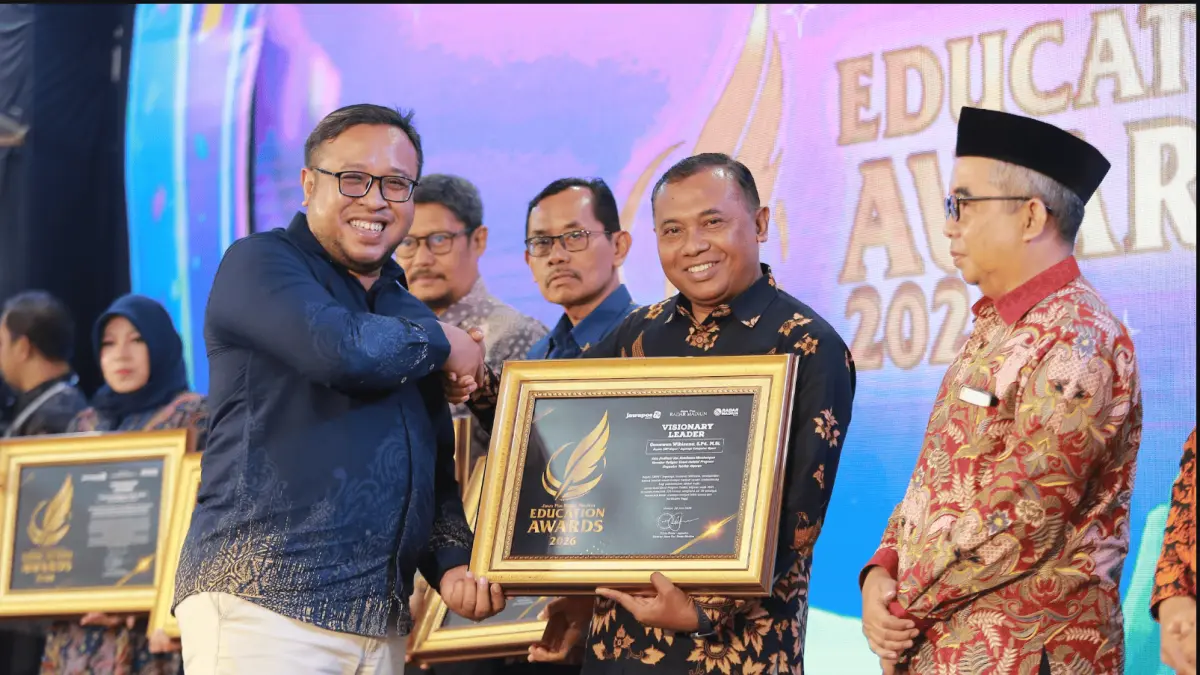 Direktur Jawa Pos Radar Madiun Ockta Prana Lagawira menyerahkan penghargaan Visionary Leader kepada Kepala SMPN 1 Jogorogo Gunawan Wibisana dalam ajang Radar Madiun Education Awards 2026, Minggu (28/6). (BAGAS BIMANTARA/RADAR MADIUN)

