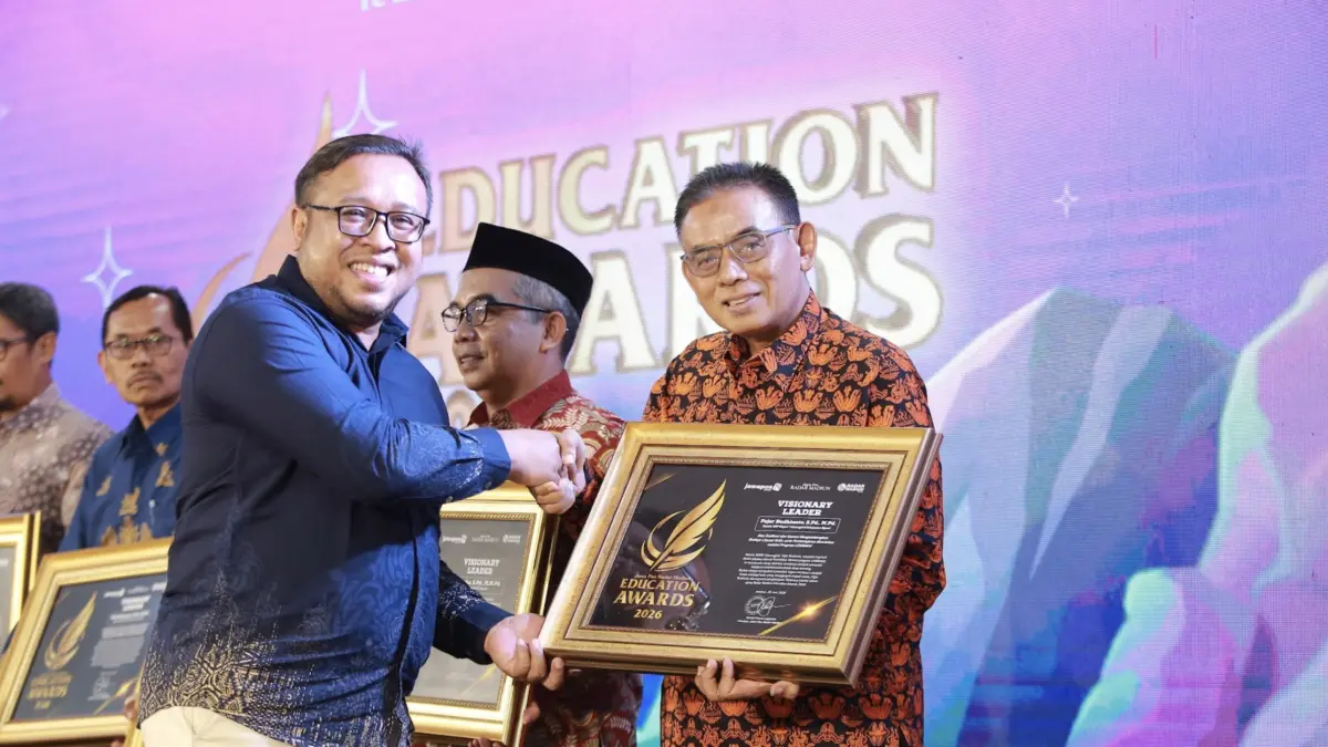 Direktur Jawa Pos Radar Madiun Ockta Prana Lagawira menyerahkan penghargaan Visionary Leader kepada Kepala SMPN 1 Karangjati Fajar Budhianto dalam ajang Radar Madiun Education Awards 2026, Minggu (28/6). (BAGAS BIMANTARA/RADAR MADIUN)