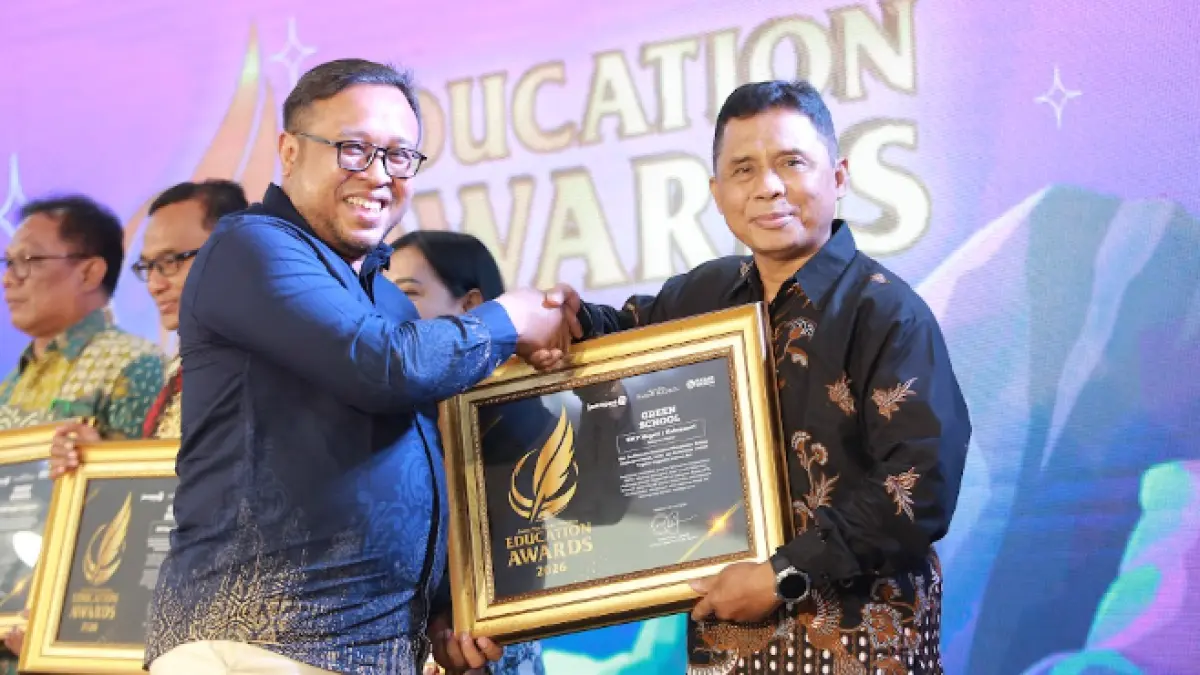 Direktur Jawa Pos Radar Madiun Ockta Prana Lagawira menyerahkan penghargaan Visionary Leader kepada Kepala SMPN 1 Kebonsari Zainal Arifin dalam ajang Radar Madiun Education Awards 2026, Minggu (28/6). (BAGAS BIMANTARA/RADAR MADIUN)