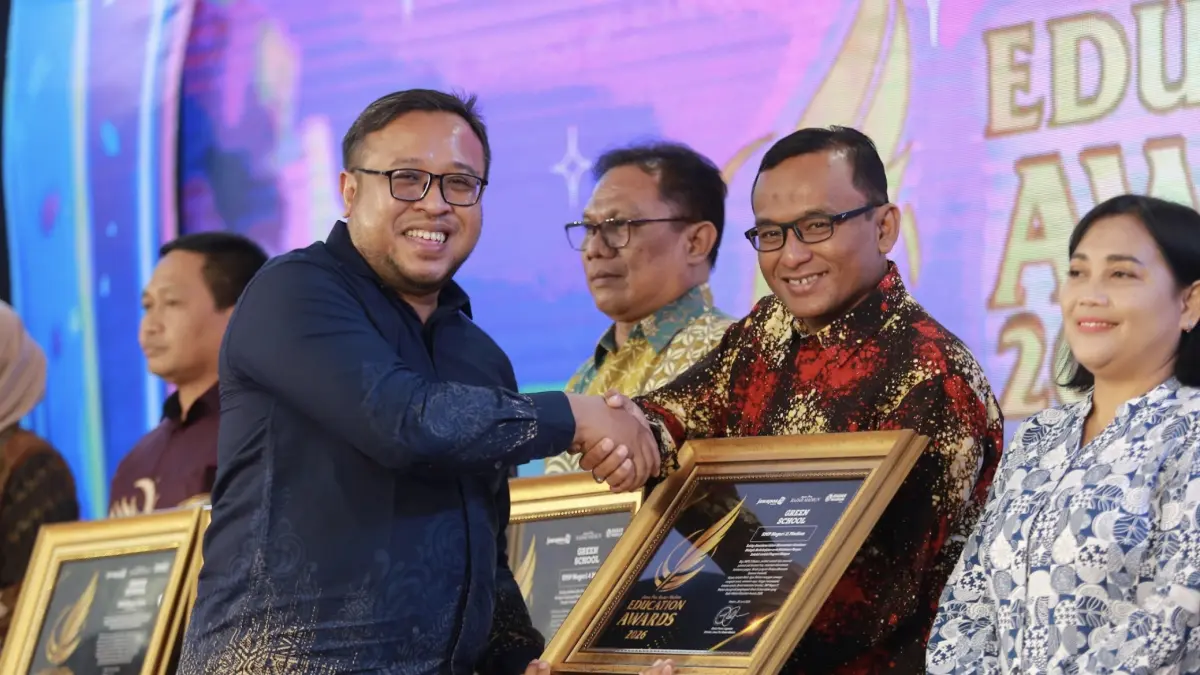 Direktur Jawa Pos Radar Madiun Ockta Prana Lagawira menyerahkan penghargaan Visionary Leader kepada Kepala SMPN 11 Madiun Agus Setiono dalam ajang Radar Madiun Education Awards 2026, Minggu (28/6).