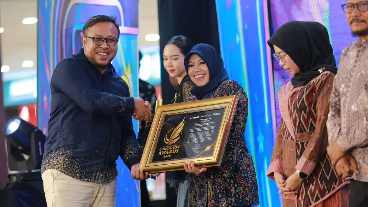 Direktur Jawa Pos Radar Madiun Ockta Prana Lagawira menyerahkan penghargaan Visionary Leader kepada Kepala SMPN 2 Madiun Eryn Irsa Ningtyas dalam ajang Radar Madiun Education Awards 2026, Minggu (28/6). (BAGAS BIMANTARA/RADAR MADIUN)