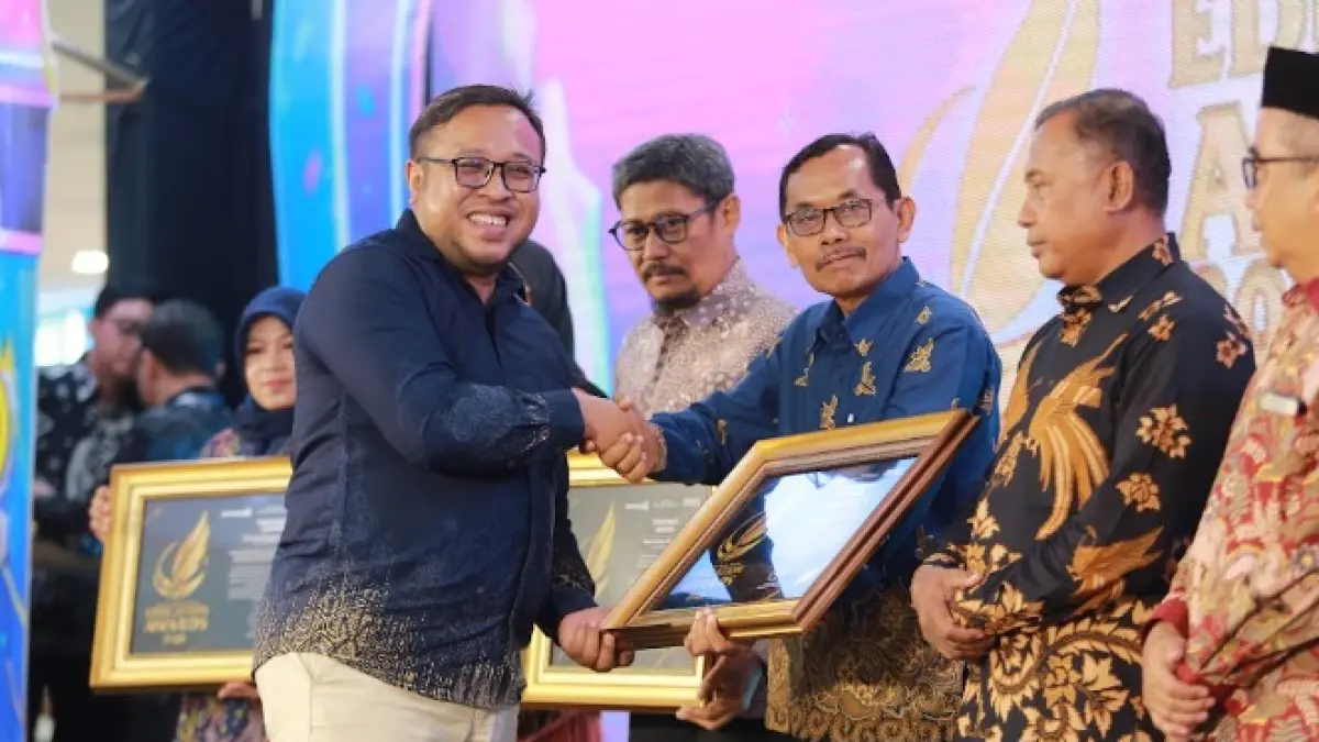 Direktur Jawa Pos Radar Madiun Ockta Prana Lagawira menyerahkan penghargaan Visionary Leader kepada Kepala SMPN 2 Mejayan Budi Santoso dalam ajang Radar Madiun Education Awards 2026, Minggu (28/6). (BAGAS BIMANTARA/RADAR MADIUN)