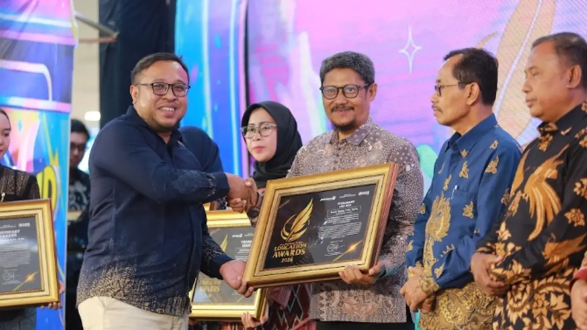 Direktur Jawa Pos Radar Madiun Ockta Prana Lagawira menyerahkan penghargaan Visionary Leader kepada Kepala SMPN 7 Madiun Sapto Usada dalam ajang Radar Madiun Education Awards 2026, Minggu (28/6). (BAGAS BIMANTARA/RADAR MADIUN)