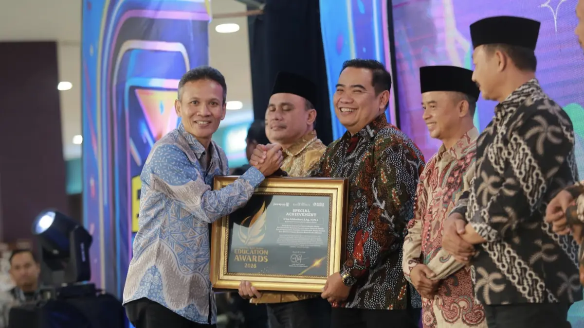 Direktur Jawa Pos Radar Marsudi Nurwahid menyerahkan penghargaan Special Achievement kepada Kepala Kantor Kemenag Kabupaten Madiun Irfan Alkhaidari dalam ajang Radar Madiun Education Awards 2026, Minggu (28/6). (BAGAS BIMANTARA/RADAR MADIUN)
