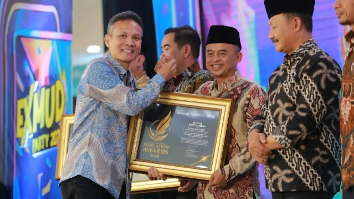 Direktur Jawa Pos Radar Marsudi Nurwahid menyerahkan penghargaan Special Achievement kepada Kepala Kantor Kemenag Ngawi Moh. Ersat dalam ajang Radar Madiun Education Awards 2026, Minggu (28/6). (BAGAS BIMANTARA/RADAR MADIUN)