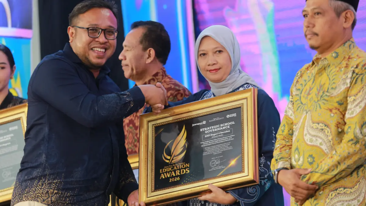Kepala SMPN 4 Saradan Sukamto yang diwakili staf menerima penghargaan Strategic School Governance dari Direktur Jawa Pos Radar Madiun Ockta Prana Lagawira pada ajang Radar Madiun Education Awards 2026. (BAGAS BIMANTARA/RADAR MADIUN)