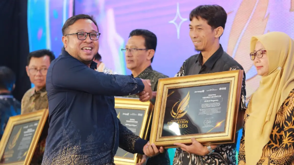Direktur Jawa Pos Radar Madiun Ockta Prana menyerahkan penghargaan Digital Transformation kepada Kepala MIN 2 Magetan Miftahul Huda dalam Radar Madiun Education Awards 2026, Minggu (28/6). (BAGAS BIMANTARA/RADAR MADIUN)
