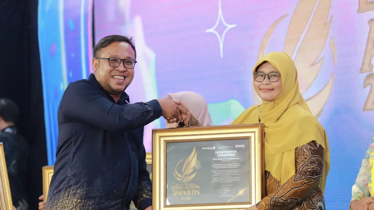 Direktur Jawa Pos Radar Madiun Ockta Prana menyerahkan penghargaan Digital Transformation kepada Kepala SMAN Pilangkenceng Kristianita Sunaringtyas dalam Radar Madiun Education Awards 2026, Minggu (28/6). (BAGAS BIMANTARA/RADAR MADIUN)