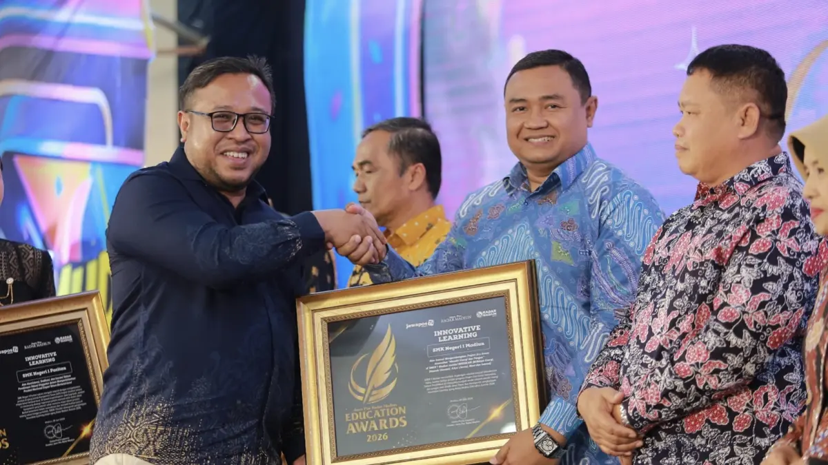 Direktur Jawa Pos Radar Madiun Ockta Prana menyerahkan penghargaan Digital Transformation kepada Kepala SMKN 1 Madiun Septa Krisdiyanto dalam Radar Madiun Education Awards 2026, Minggu (28/6). (BAGAS BIMANTARA/RADAR MADIUN)