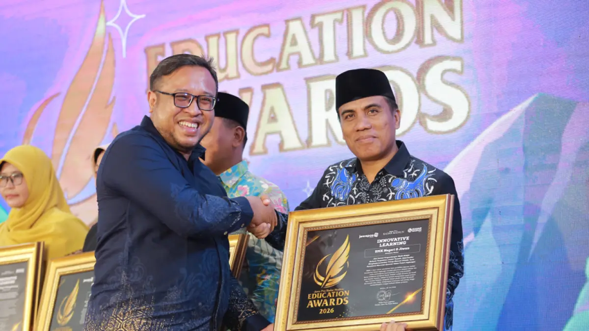 Direktur Jawa Pos Radar Madiun Ockta Prana menyerahkan penghargaan Digital Transformation kepada Kepala SMKN 2 Jiwan Lamijan dalam Radar Madiun Education Awards 2026, Minggu (28/6). (BAGAS BIMANTARA/RADAR MADIUN)
