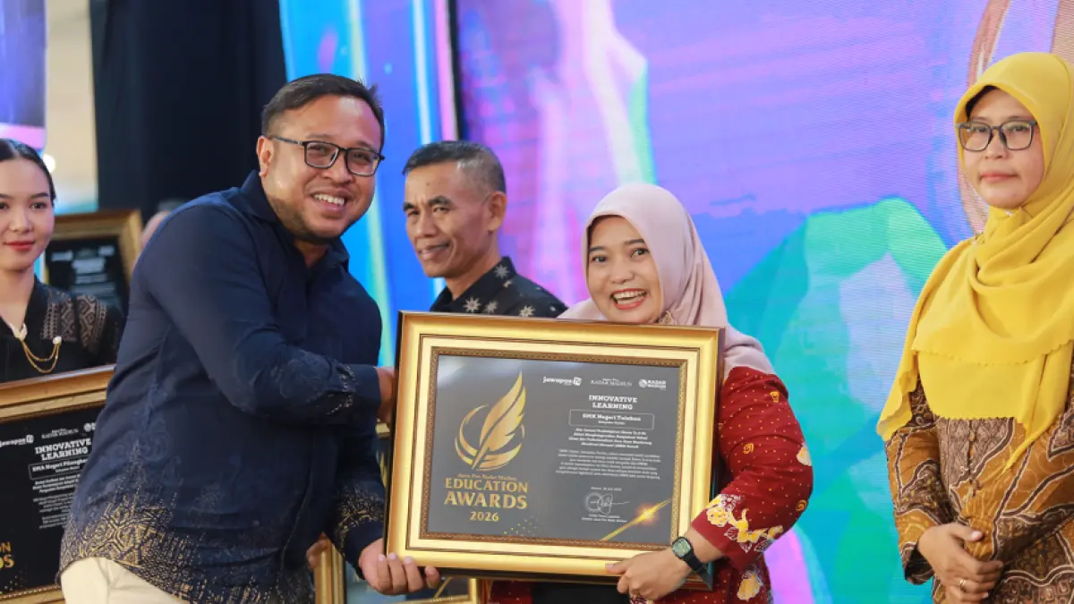 Direktur Jawa Pos Radar Madiun Ockta Prana menyerahkan penghargaan Digital Transformation kepada Kepala SMKN Tulakan Evi Dhian Asmoro dalam Radar Madiun Education Awards 2026, Minggu (28/6). (BAGAS BIMANTARA/RADAR MADIUN)