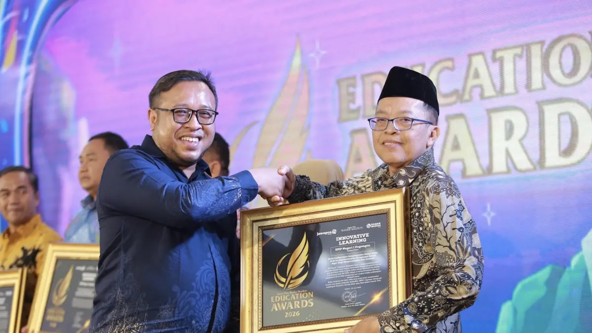 Direktur Jawa Pos Radar Madiun Ockta Prana menyerahkan penghargaan Digital Transformation kepada Kepala SMPN 1 Dagangan Sulistya Dwi Susanto dalam Radar Madiun Education Awards 2026, Minggu (28/6). (BAGAS BIMANTARA/RADAR MADIUN)