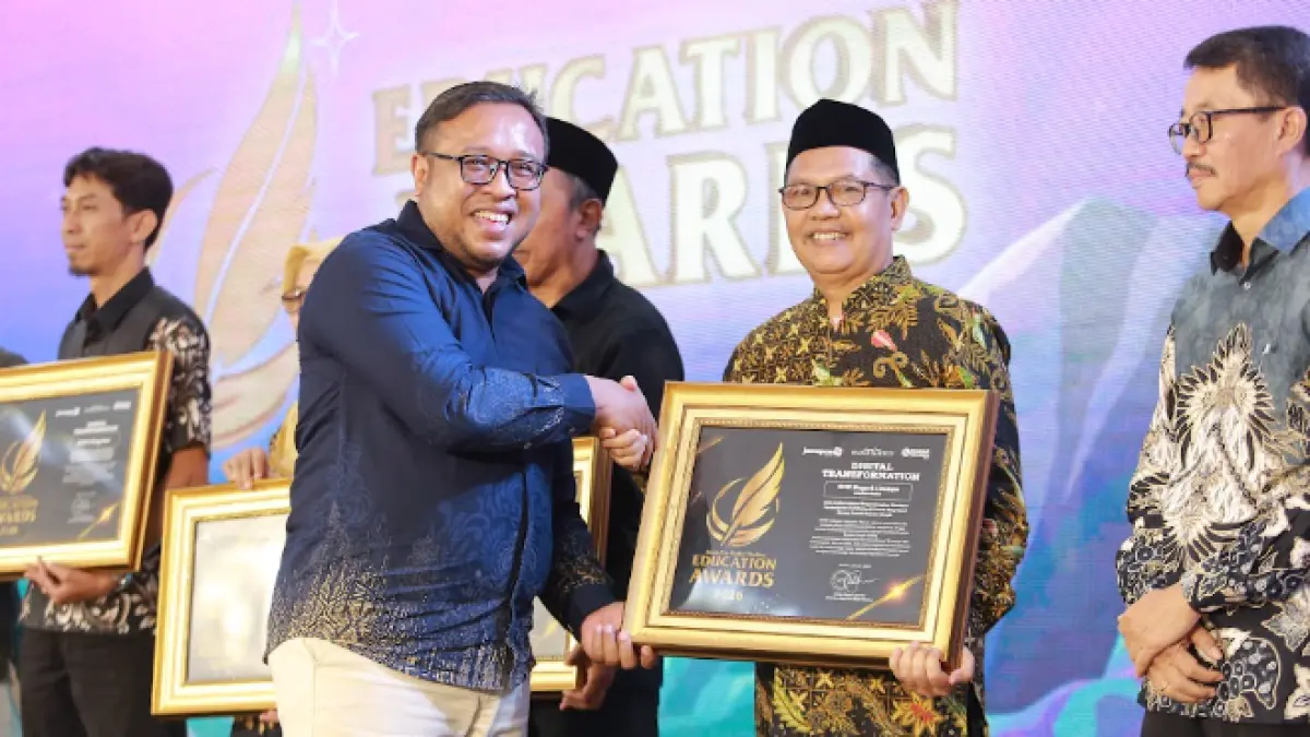 Direktur Jawa Pos Radar Madiun Ockta Prana menyerahkan penghargaan Digital Transformation kepada Kepala SMPN 1 Dolopo, Arif Wardoyo dalam Radar Madiun Education Awards 2026, Minggu (28/6). (BAGAS BIMANTARA/RADAR MADIUN)