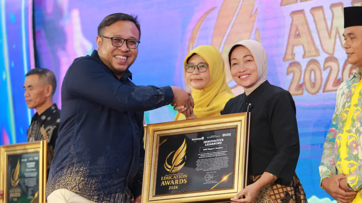 Direktur Jawa Pos Radar Madiun Ockta Prana menyerahkan penghargaan Digital Transformation kepada Kepala SMPN 1 Madiun Esti Nurhayati dalam Radar Madiun Education Awards 2026, Minggu (28/6). (BAGAS BIMANTARA/RADAR MADIUN)