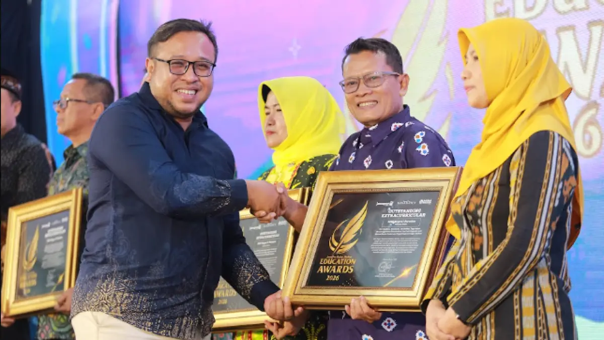 Direktur Jawa Pos Radar Madiun Ockta Prana menyerahkan penghargaan Digital Transformation kepada  Kepala SMPN 1 Saradan, Warso,dalam Radar Madiun Education Awards 2026, Minggu (28/6). (BAGAS BIMANTARA/RADAR MADIUN)