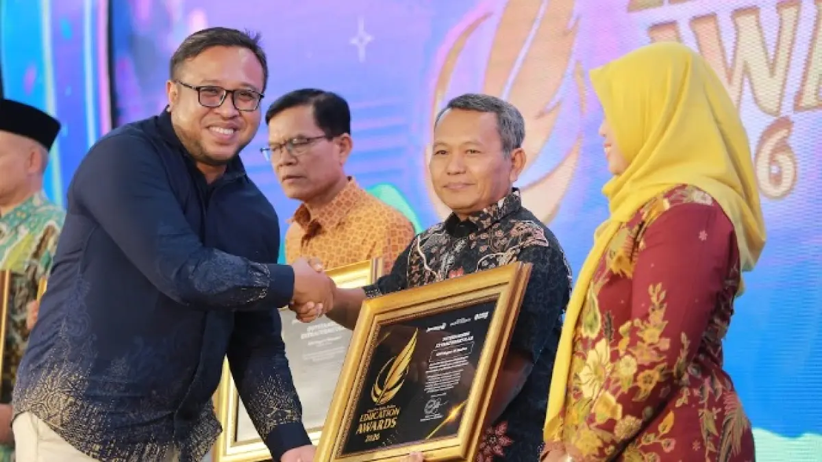 Direktur Jawa Pos Radar Madiun Ockta Prana menyerahkan penghargaan Digital Transformation kepada Kepala SMPN 12 Madiun Sudjani dalam Radar Madiun Education Awards 2026, Minggu (28/6). (BAGAS BIMANTARA/RADAR MADIUN)