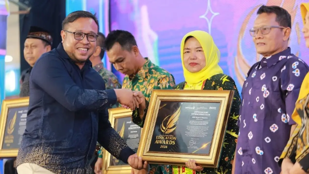 Direktur Jawa Pos Radar Madiun Ockta Prana menyerahkan penghargaan Digital Transformation kepada Plt Kepala SMPN 1 Mejayan Minarti dalam Radar Madiun Education Awards 2026, Minggu (28/6). (BAGAS BIMANTARA/RADAR MADIUN)