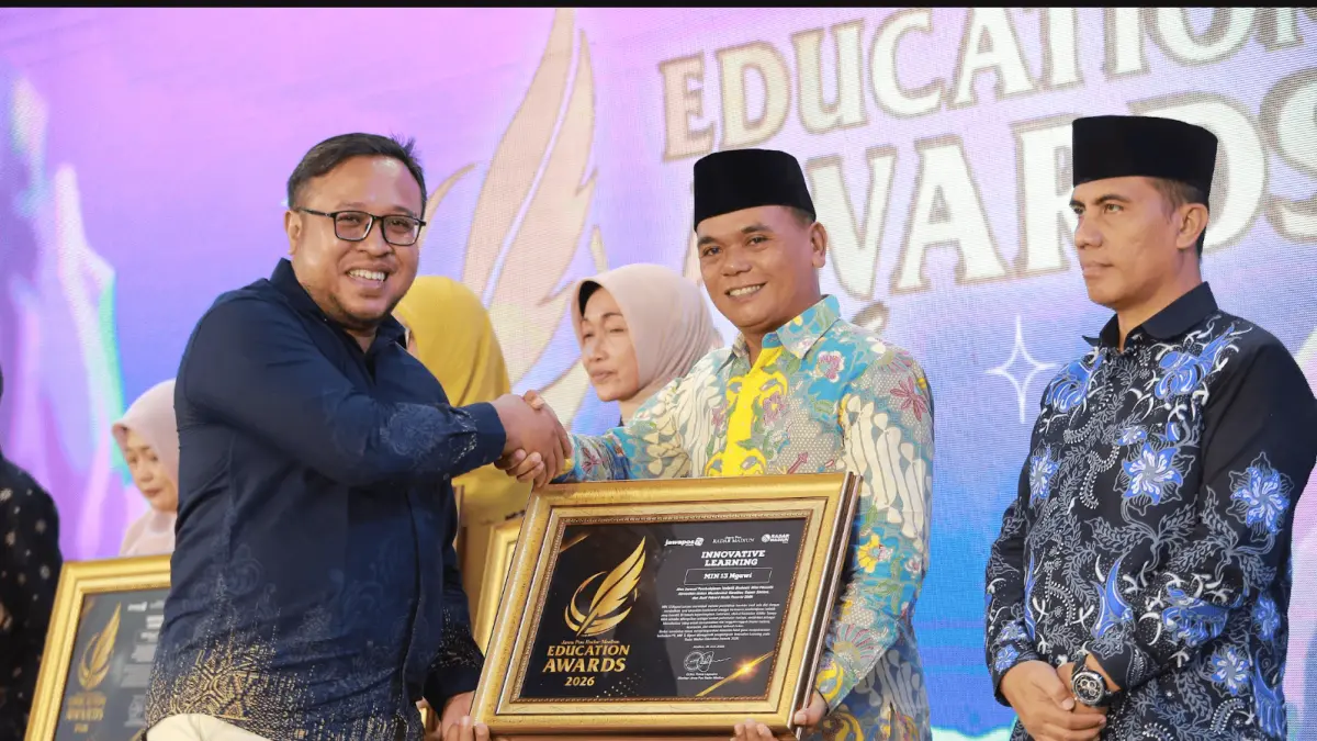 Kepala MIN 13 Ngawi Sukarwan menerima penghargaan Innovative Learning dari Direktur Jawa Pos Radar Madiun Ockta Prana Lagawira dalam Radar Madiun Education Awards 2026. (BAGAS BIMANTARA/RADAR MADIUN)