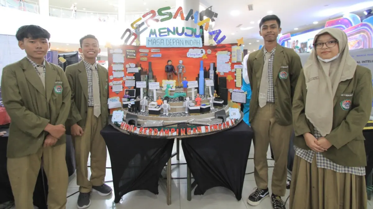 Tim MAN 1 Magetan menunjukkan mading bertema "Berdampingan AI Menuju Masa Depan Indah" yang mengantarkan mereka meraih Juara I Lomba Mading 3D Exmud Party 2026 dengan memanfaatkan sekitar 70 persen bahan daur ulang. BAGAS BIMANTARA/RADAR MADIUN