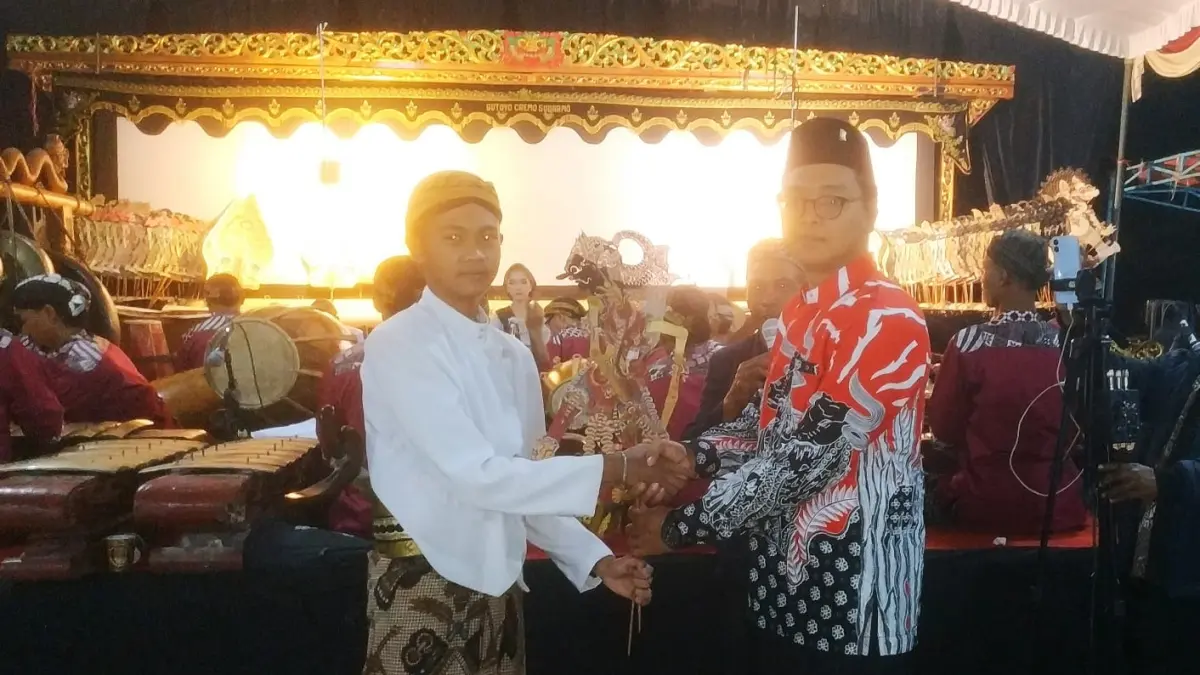 SERAHKAN: Kepala Desa Setono Pradana Digdya Wahana menyerahkan wayang kepada dalang penanda dimulainya pagelaran wayang kulit. (SATRIO JATI/RADAR MADIUN)