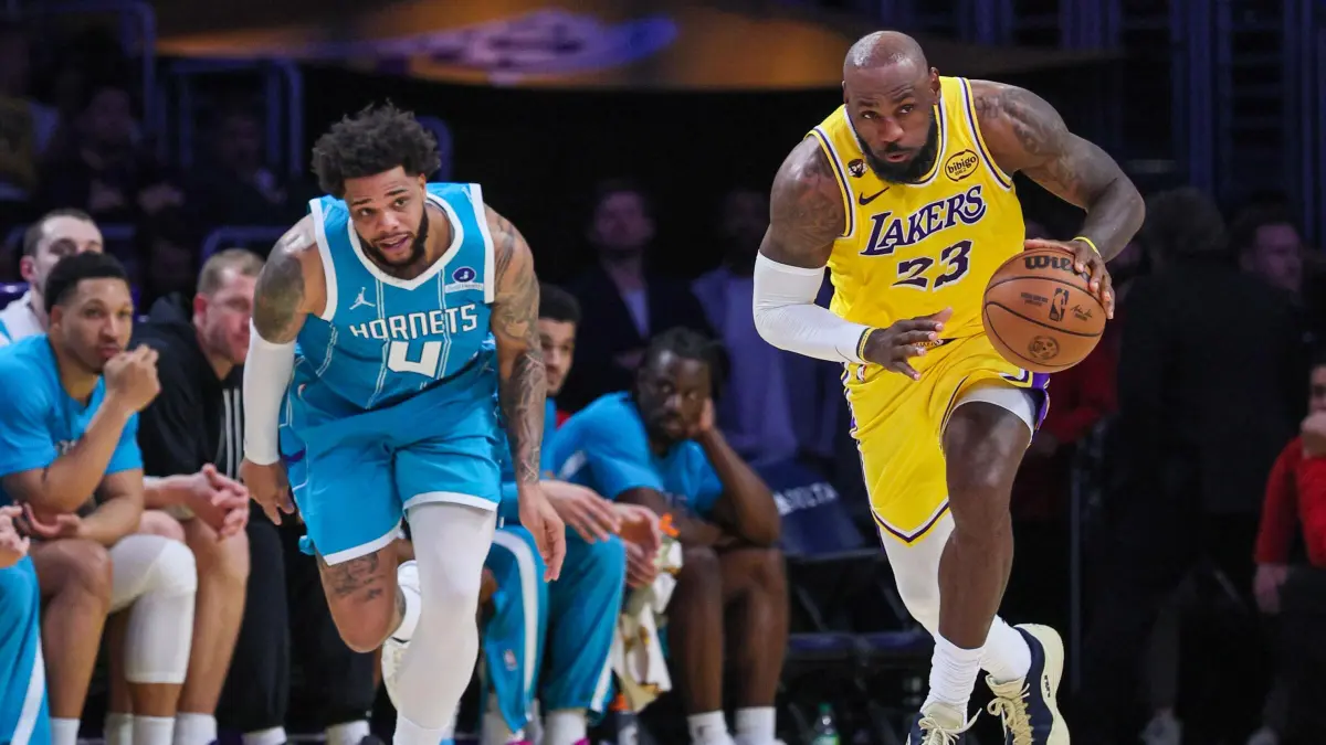LeBron James membawa bola sembari dikejar oleh guard Hornets, Sion James. (latimes.com)