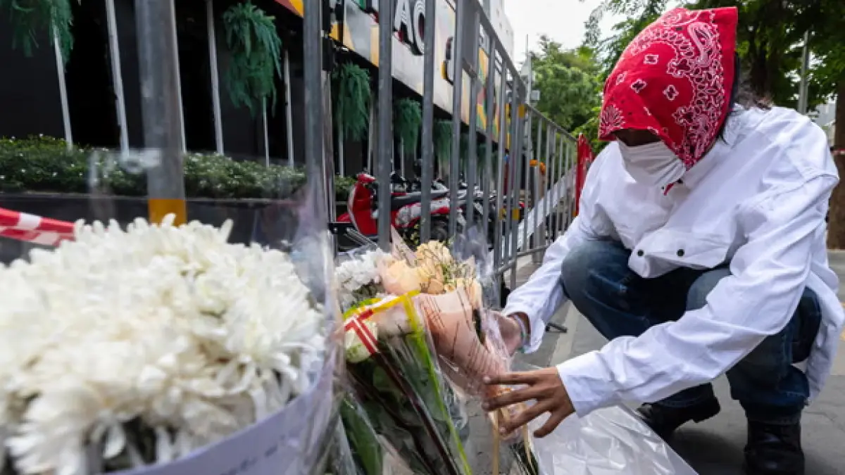 A man places flowers outside the the Rong Beer Na Ladprao pub in Bangkok, where at least 30 people died in a fire. (The Guardian)
