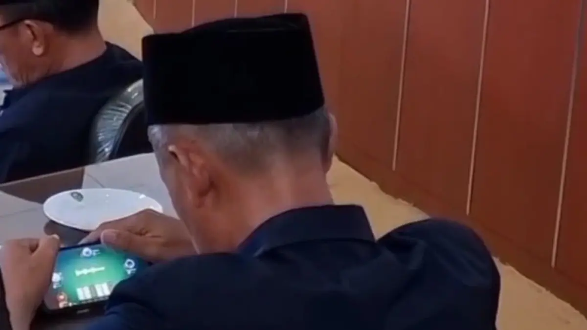 VIRAL: Tangkapan layar video yang memperlihatkan seorang camat bermain game di ruang rapat paripurna DPRD Kabupaten Madiun.