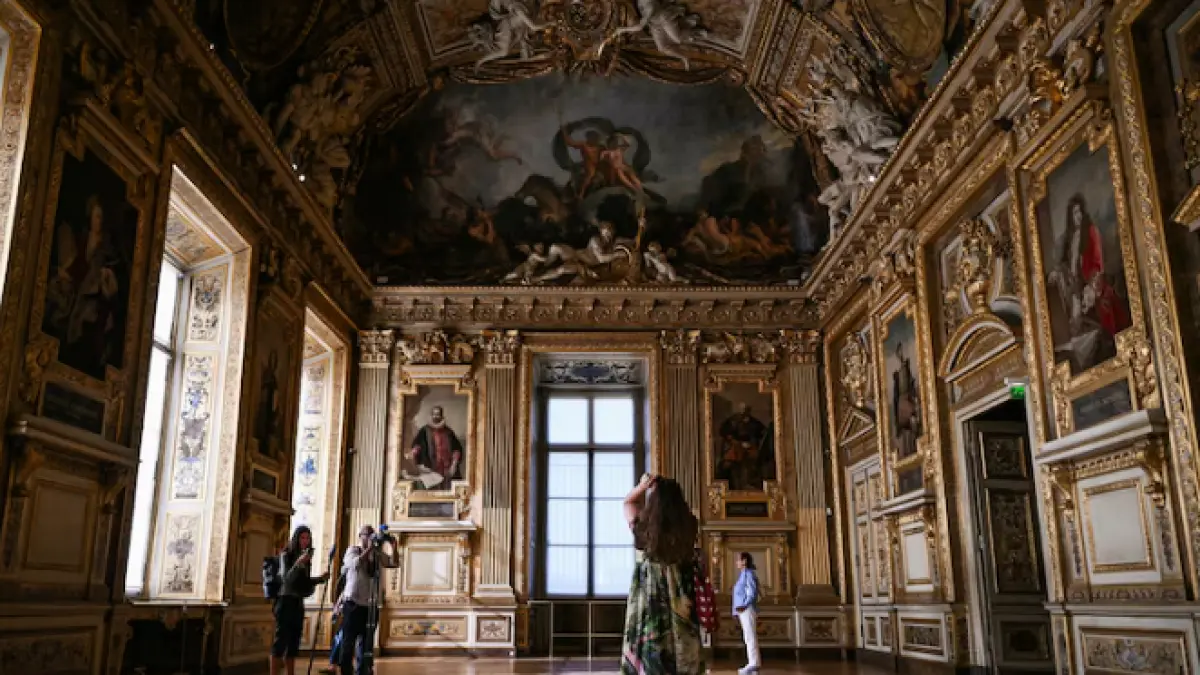 Visitors take a picture of the window which was broken during the reopening to the public of the Apollo Gallery, where French crown jewels worth 88 million euros were stolen in 2025 in a brazen heist, at the Musee du Louvre in Paris on July 22, 2026. (ABC News)
