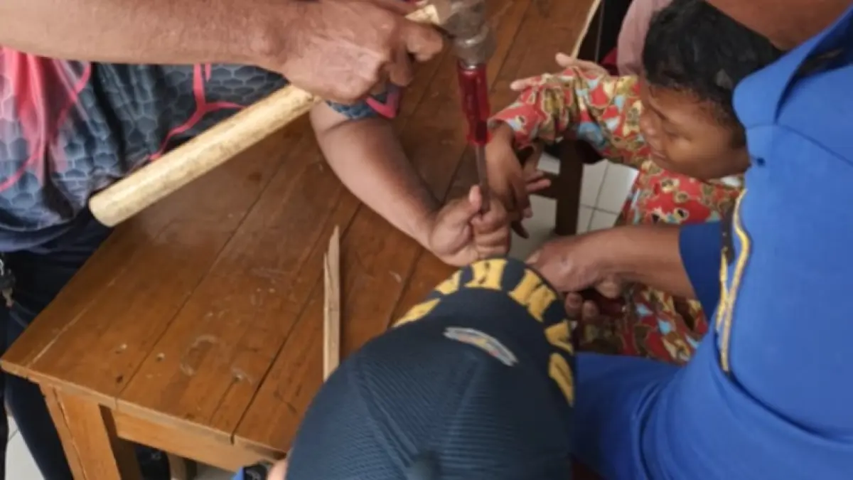 EVAKUASI: Petugas Damkar Kabupaten Madiun membebaskan jari telunjuk seorang siswa SDN Bangunsari 03 yang terjepit di lubang meja belajar. FOTO: DAMKAR MADIUN