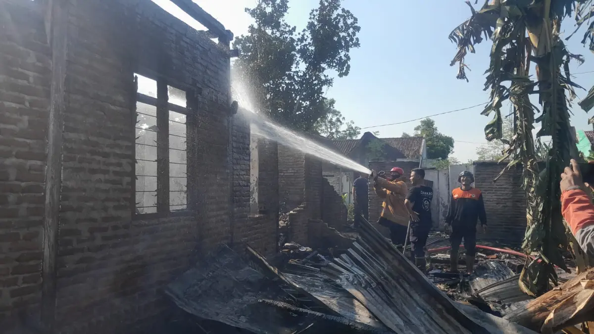 PADAMKAN API: Petugas Damkarmat Satpol PP Ngawi memadamkan kebakaran rumah warga. (Asep Syaeful Bachri/Jawa Pos Radar Ngawi)