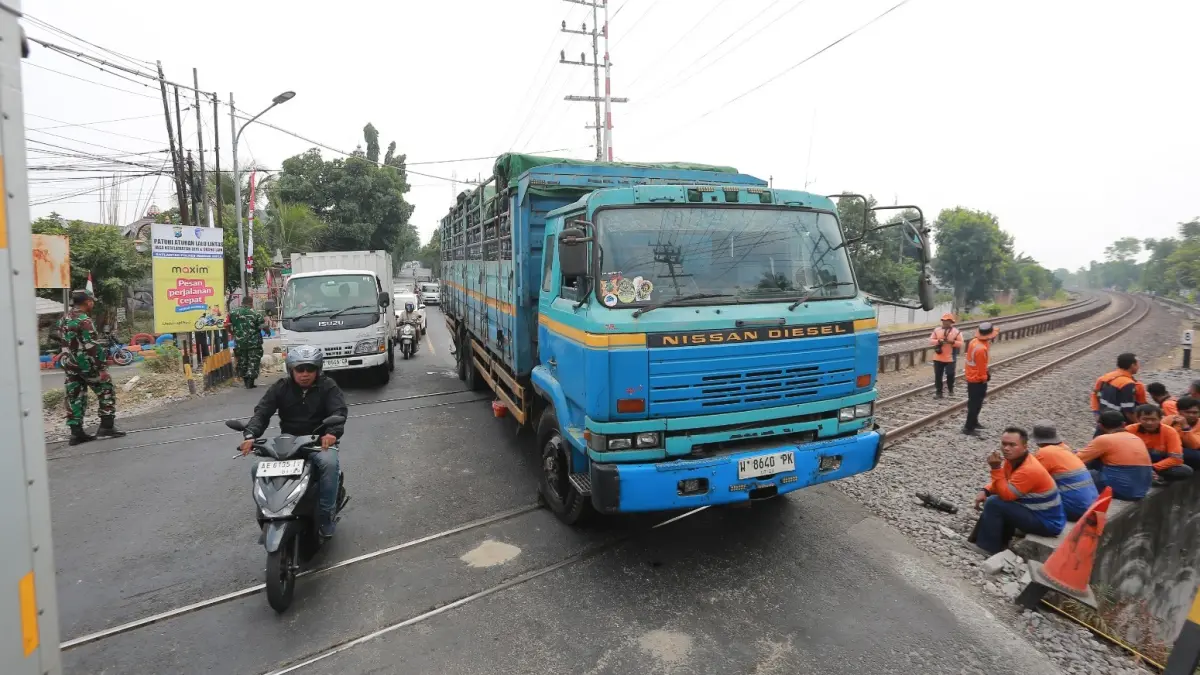 REKAYASA LALIN: Truk tronton bermuatan sekitar 20 ton galon air mineral mogok di perlintasan KA Sukosari, Kota Madiun, Selasa (18/8). Polisi menerapkan contra flow selama proses penanganan. (Bagas Bimantara/Jawa Pos Radar Madiun)