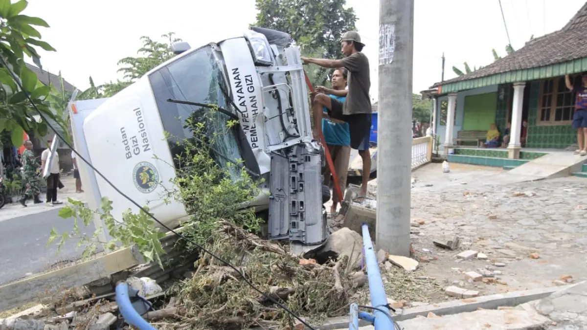 TERGULING: Mobil SPPG Lembeyan Wetan terguling setelah menghantam pagar rumah warga di Desa Krowe, Magetan, Rabu (19/8). AJI PUTRA/RADAR MAGETAN