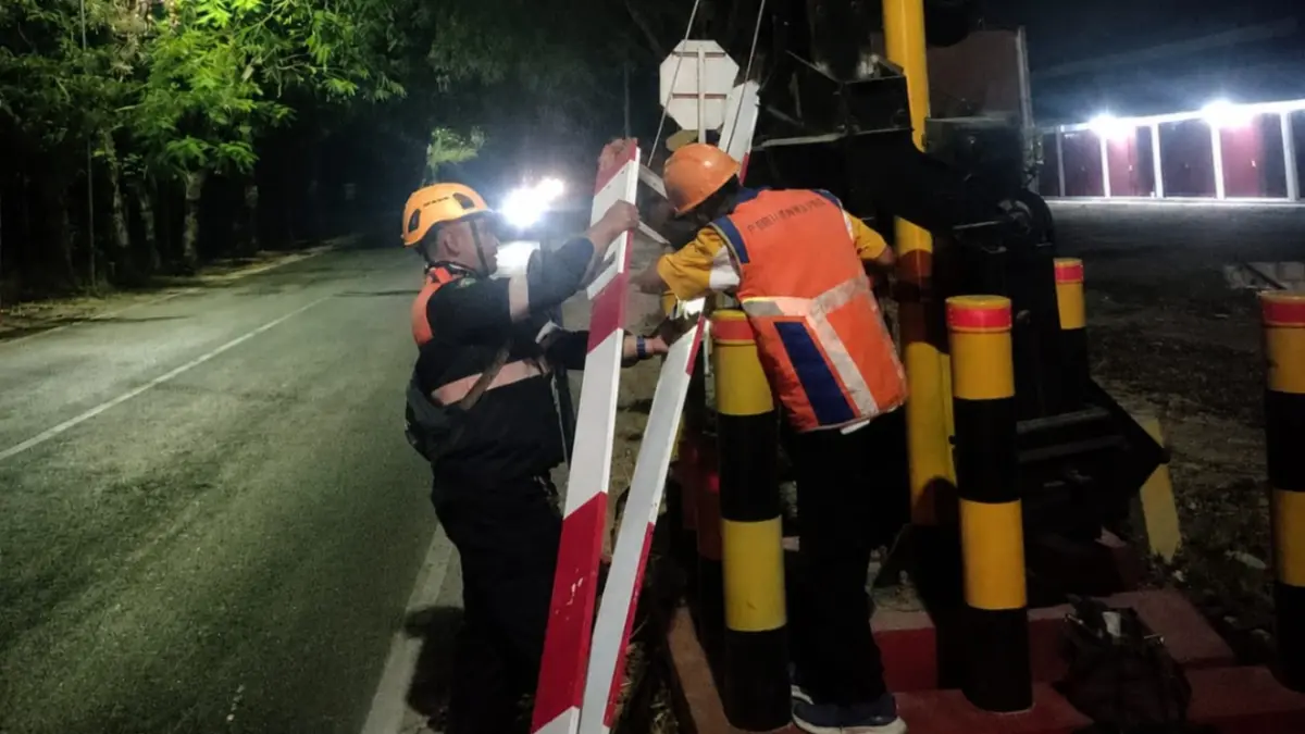 RUSAK: Petugas menangani palang perlintasan KA di JPL 15 petak Geneng–Magetan setelah ditabrak pengendara sepeda motor, Sabtu (29/8) dini hari.