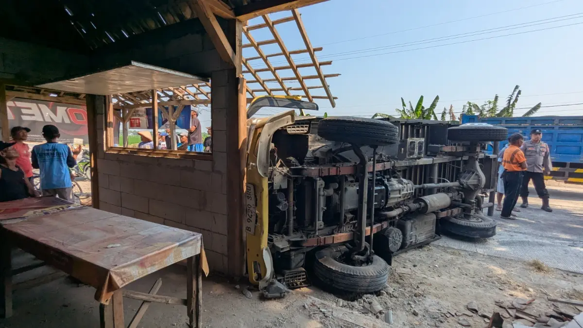 TERGULING: Kondisi truk boks pengangkut sembako untuk salah satu SPPG di Geneng setelah terguling dan menghantam warung serta sepeda motor di Jalan Ngawi–Kwadungan, Desa Dinden, Kwadungan, Rabu (2/9). Asep Syaeful Bachri/Jawa Pos Radar Ngawi