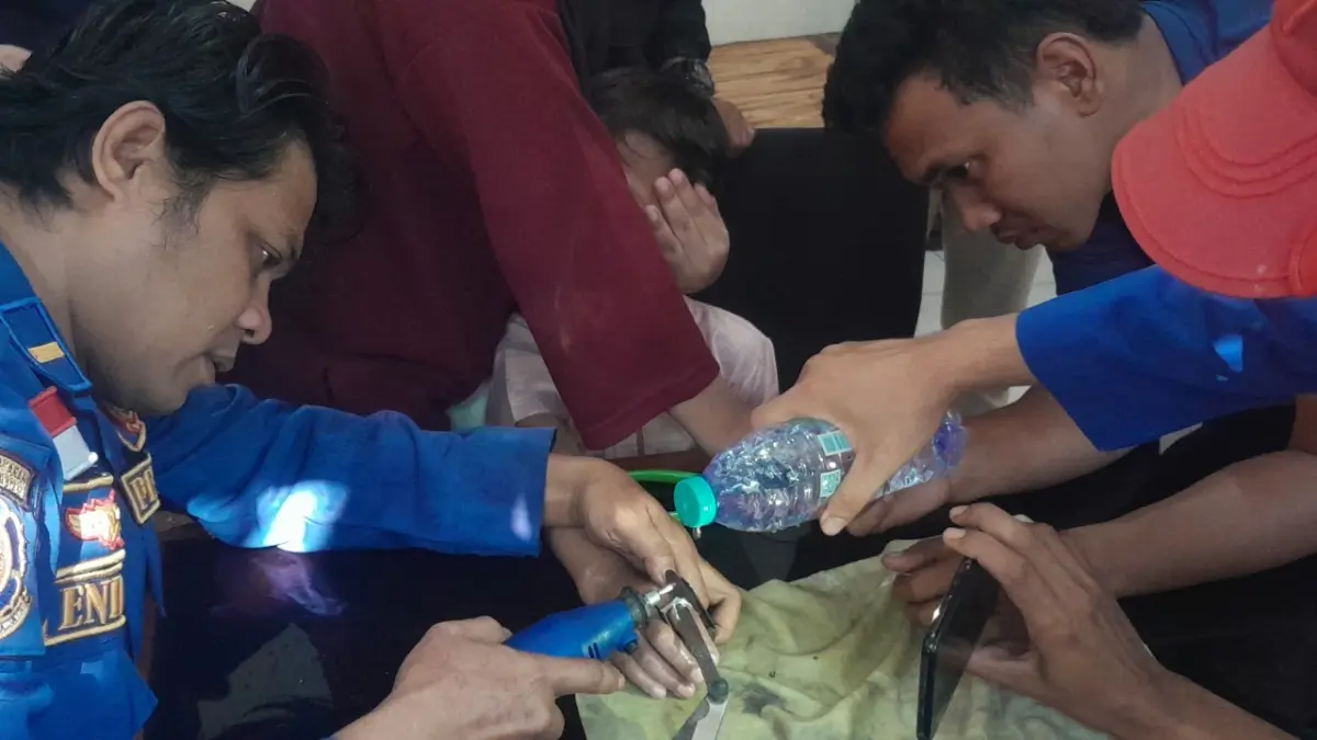 CUKUP SULIT: Petugas Damkar Satpol PP Ngawi mengevakuasi jari Raihan Denis yang terjepit kepala sabuk menggunakan gerinda kecil, Kamis (3/9).