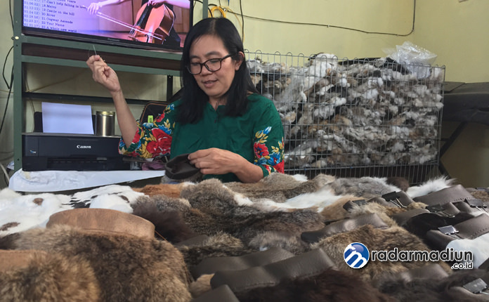 KREATIF: Tri Suharlina saat menjahit kantong berbahan kulit kelinci yang dipadupadankan dengan kulit sapi sintetis.