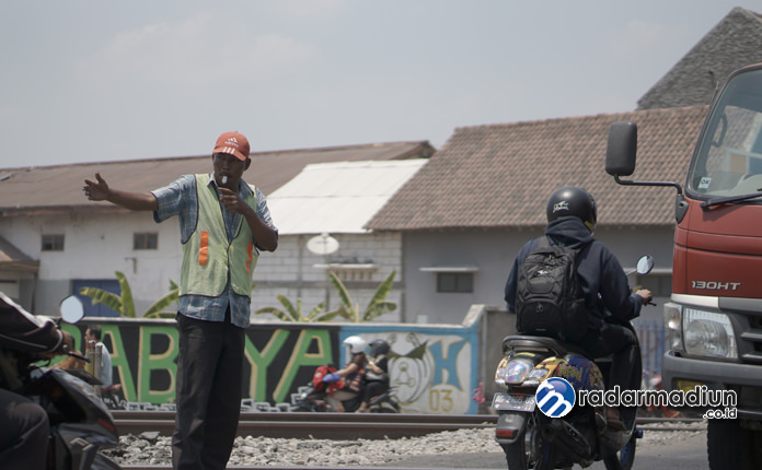 MENAHUN: Heru Dasiman sedang mengatur lalu lintas di perlintasan kereta Wonoasri.