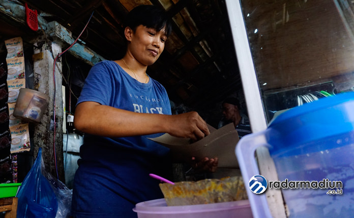 TURUN-TEMURUN: Siti Khomariah sedang melayani pelanggan di warungnya. (TEGAR RUKMANA/RADAR MADIUN)
