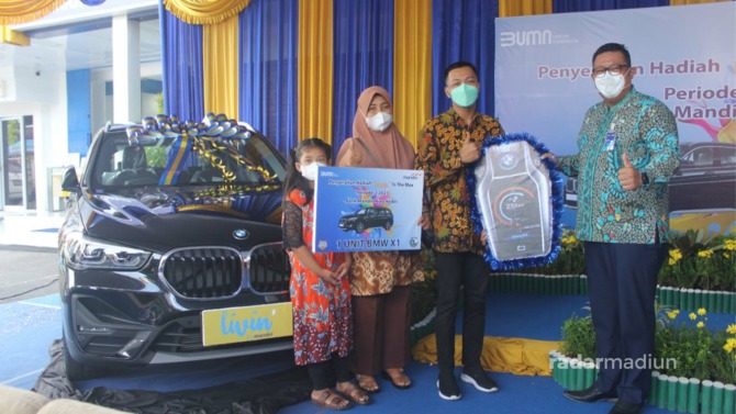 BERUNTUNG: Vice President Bank Mandiri Area Kediri Ananditho J. Prakoso (kanan) memberikan secara simbolis hadiah 1 unit mobil BMW X1 kepada Eko Aji Santoso di Senin (27/12). (APRILIA FITRI/JAWA POS RADAR MADIUN)