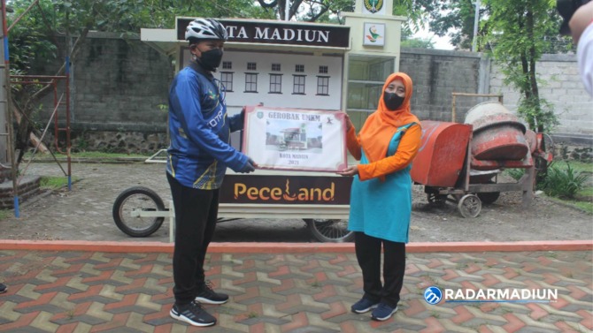 EKONOMI: Wali Kota Madiun Maidi menyerahkan secara simbolis bantuan gerobak UMKM kepada perwakilan PKK Kelurahan Ngegong  Siti Mukoyaroh di lapak Ronggo Kuning, kemarin.