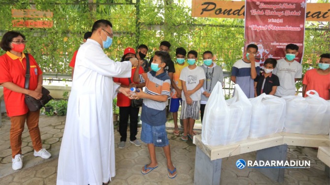 BERBAGI: Panitia Natal Gereja St. Cornelius saat membagikan paket makanan kepada warga. (BAGAS BIMANTARA/JAWA POS RADAR MADIUN)