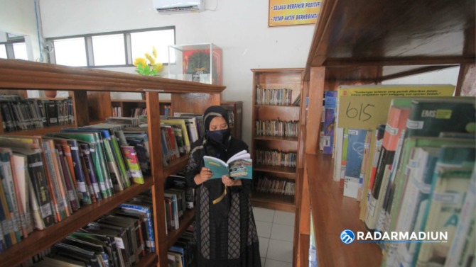 BACA BUKU: Seorang warga ketika berkunjung dan melihat koleksi buku Perpusda Ponorogo. (AJI PUTRA/RADAR PONOROGO)
