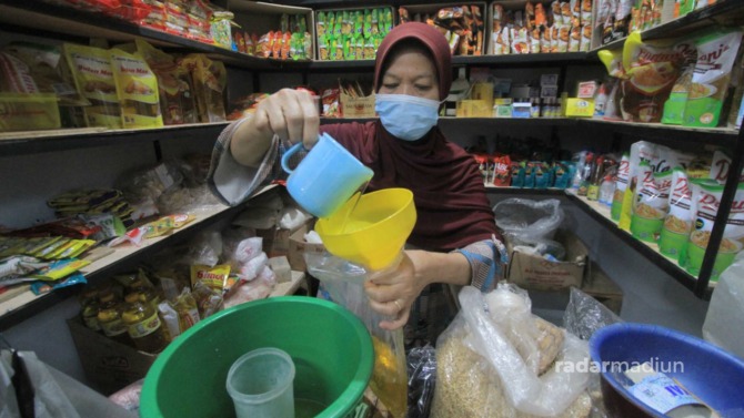 MAHAL: Pedagang di Pasar Legi Ponorogo menakar minyak goreng curah yang dijualnya. (AJI PUTRA/JAWA POS RADAR PONOROGO)