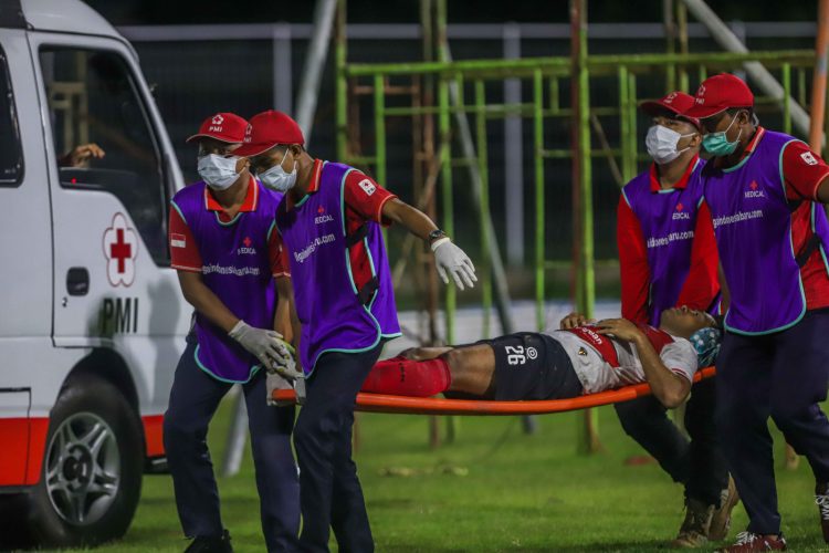 Bek Madura United Novan Setya Sasongko ditandu menuju ambulans setelah berbenturan dengan kapten Persebaya Rachmat Irianto. (Riana Setiawan/Jawa Pos)
